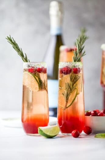 两个并排的玻璃杯装满了简单的蔓越莓含羞草配方和装饰