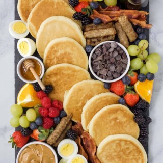 一种熟食板，里面有一串早餐食物，包括煎饼和枫糖浆