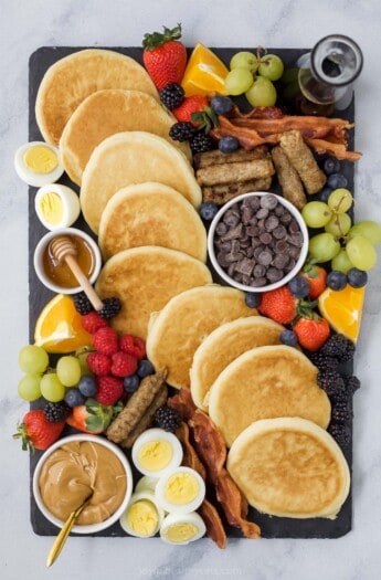 一种熟食板，里面有一串早餐食物，包括煎饼和枫糖浆